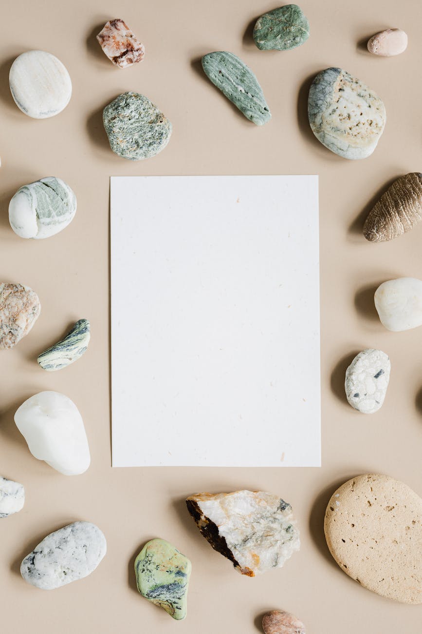 blank white sheet of paper on beige surface with stones